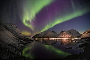 Travel to see the northern lights near snow coated mountains