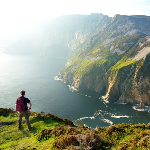 Man standing near side of cliff looking out over the water below