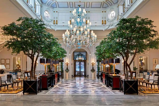 luxury lobby with marble floor and trees lining walk way